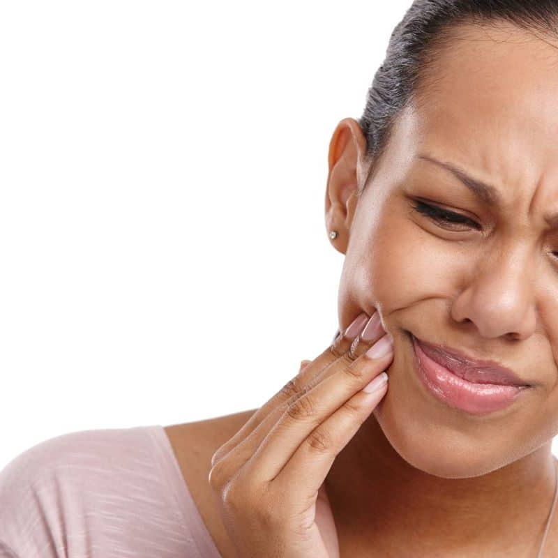 Woman touching cheek in pain, appears to have toothache