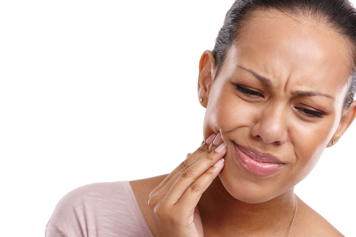 Woman touching cheek in pain, appears to have toothache