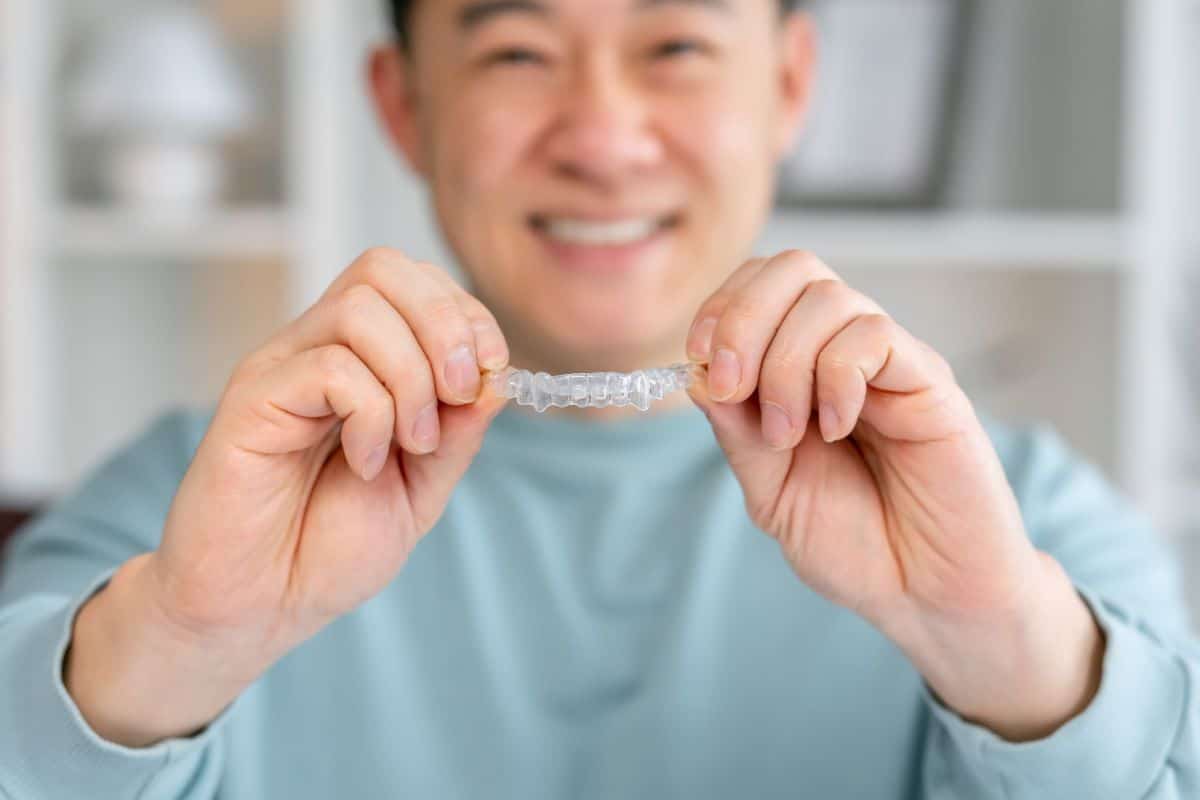 Man smiling, holding clear dental aligner in Reno & Sparks, Nevada