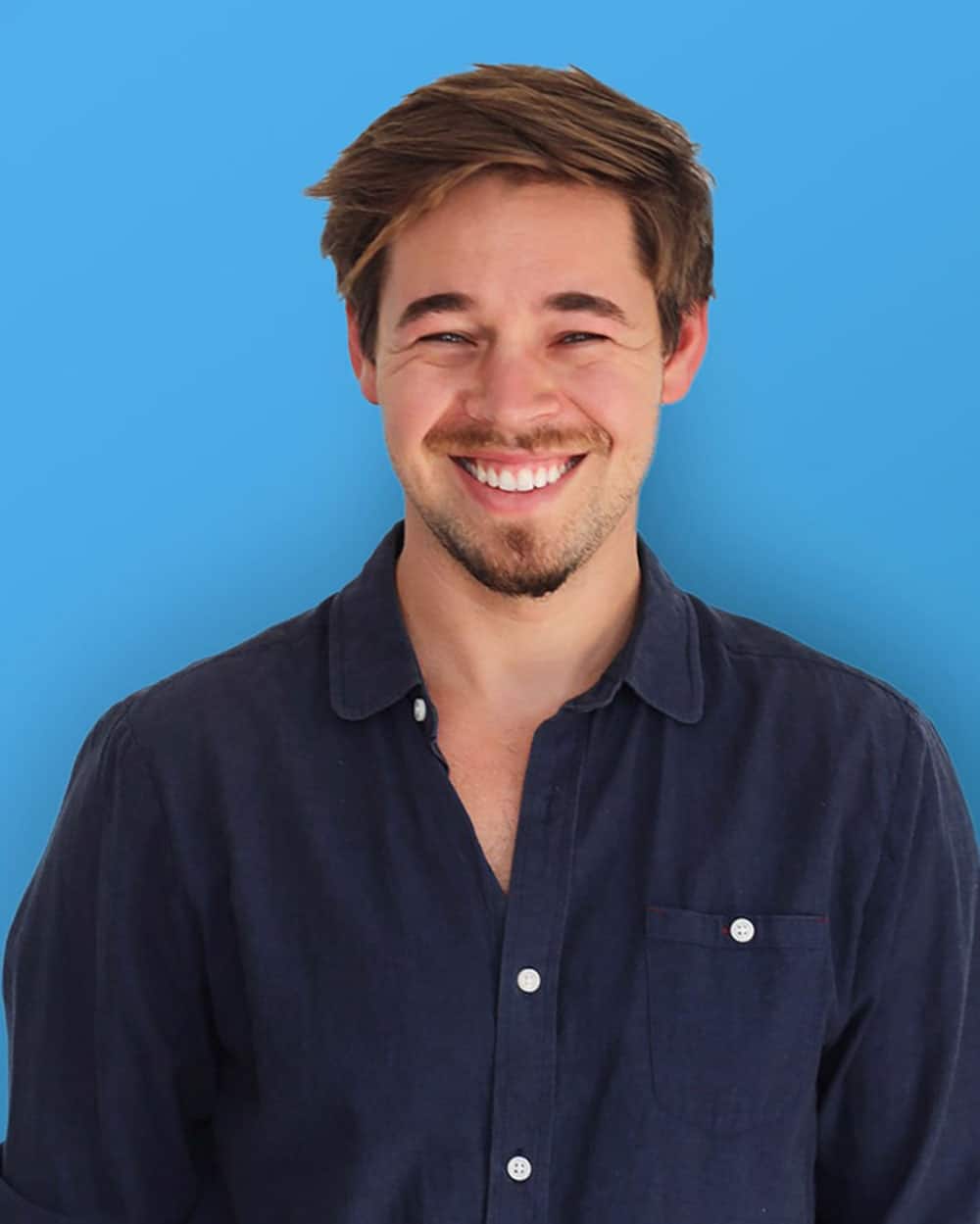 Smiling man in dark shirt against blue background