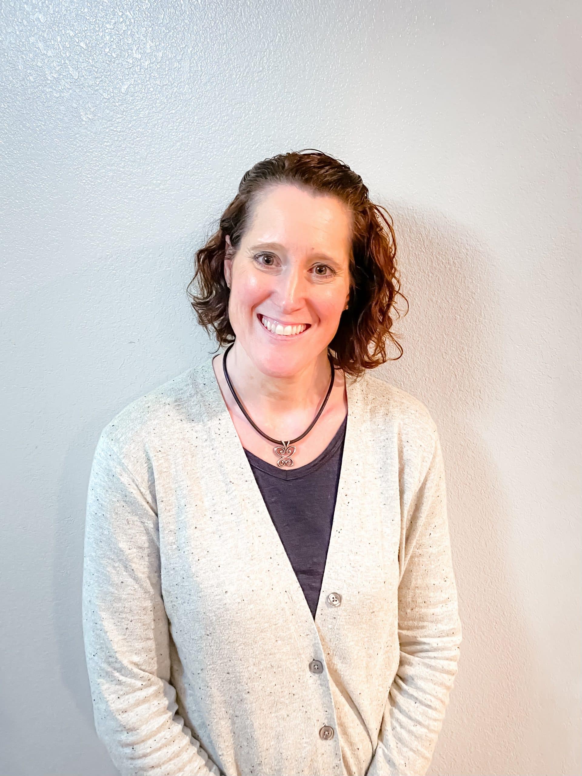 Smiling woman with curly hair in gray cardigan