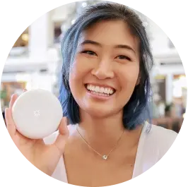 Woman smiling, holding a compact product in store