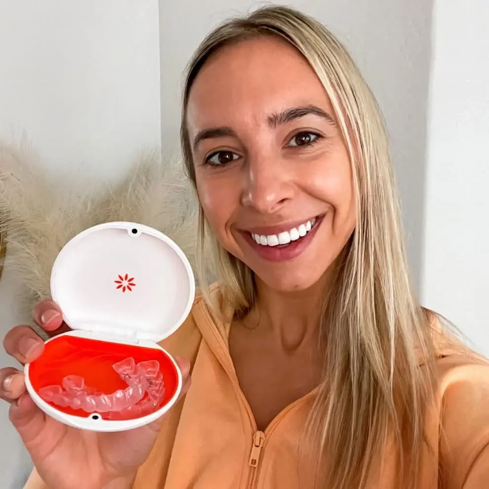 Woman smiling, holding open case with dental aligners